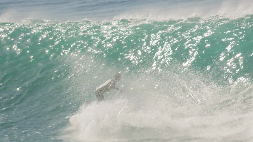 Male surfer surfs a wave as it comes towards land