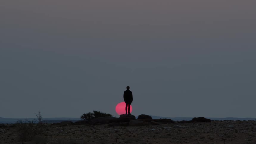 Man standing on a rock watches the red moon