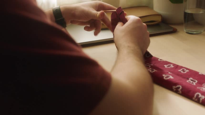 A white man puts a rubber band around a piece of fabric