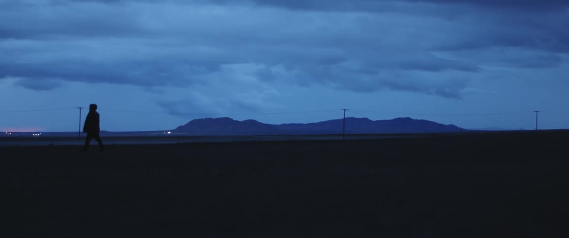 Silhouette of a man walks in the field at dusk