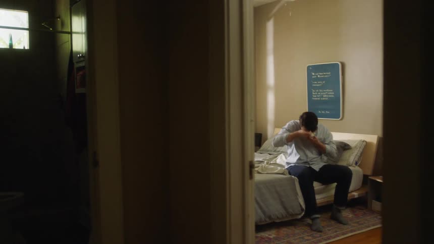 Man sitting on the bed wears a face mask and gets out of the bedroom