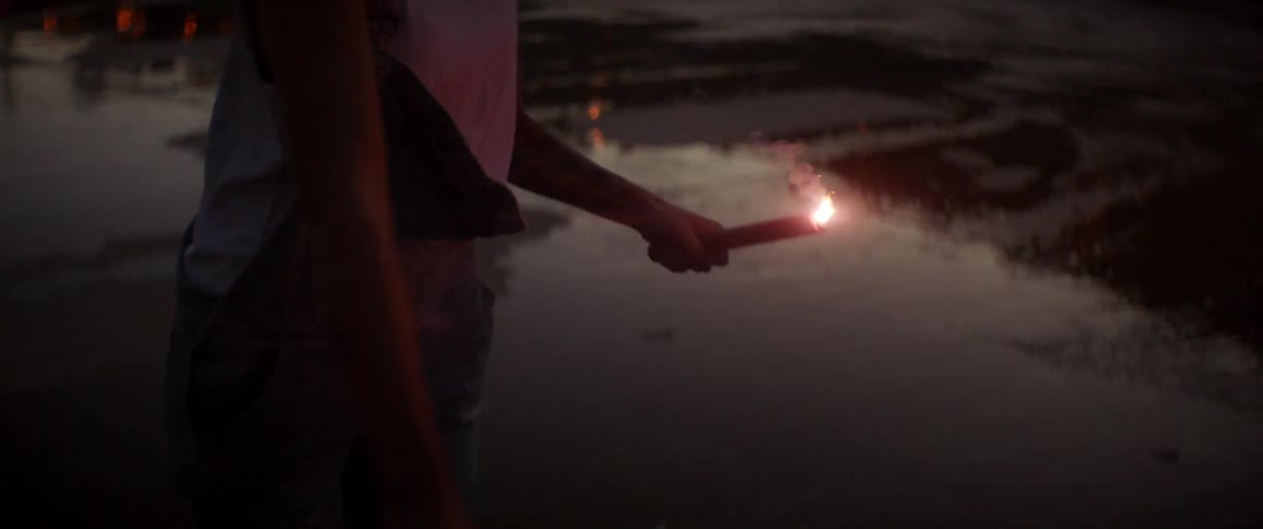 A man holds a flare and lights it