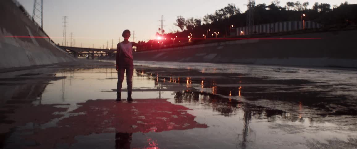 Woman standing in a wash holding a flare at dusk