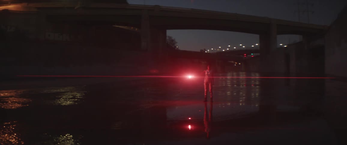 A human being holds up a burning flare while standing in the los angeles river