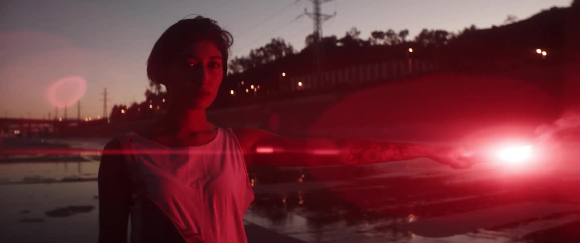 A teenager stands on a road and holds a burning flare