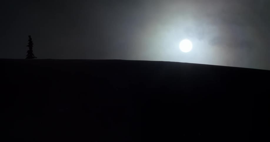 The sun is above the hill behind the clouds