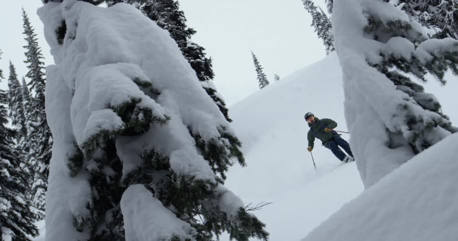 A skier rides down a steep snow covered slope