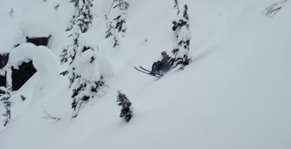 A skier jumps off a cliff surrounded by trees