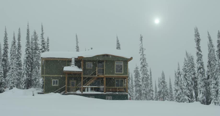 A lodge in the forest under falling snow