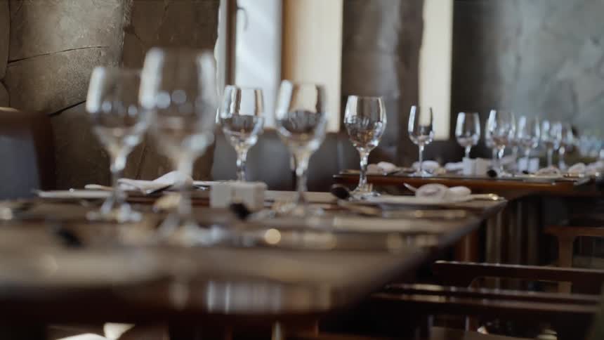 Several tables in a restaurant are set with wine glasses and silverware