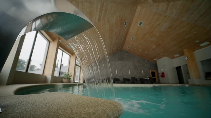 A luxurious indoor pool with a fountain pouring water into it