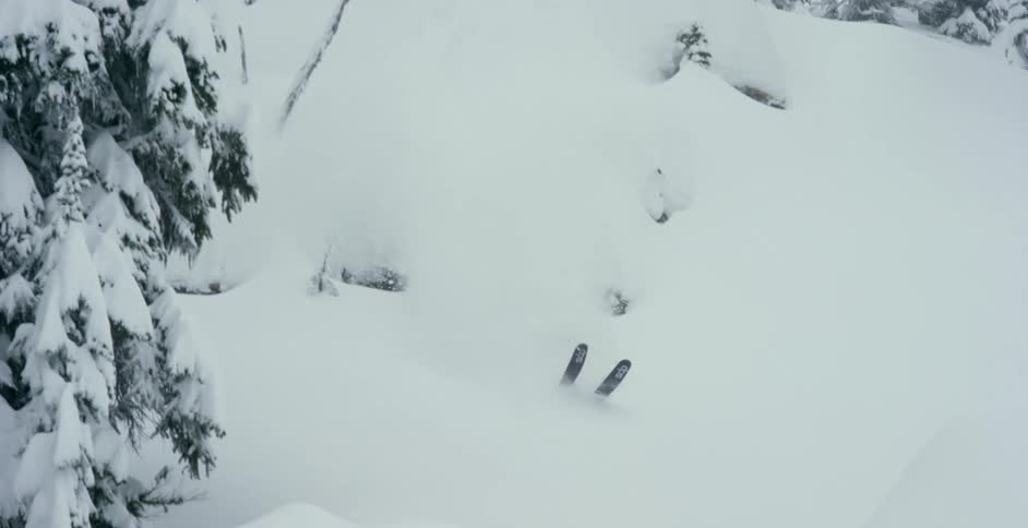 A skier descending a cliff in deep powder