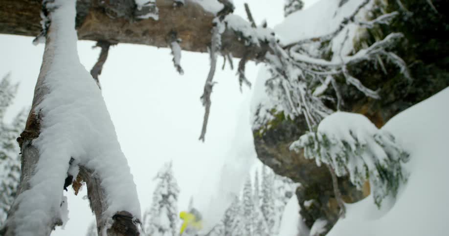 A skier jumps down a powdery cliff