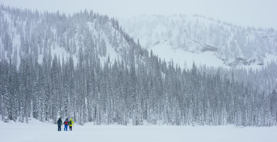 People walk across a frozen lake towards a snowy mountain