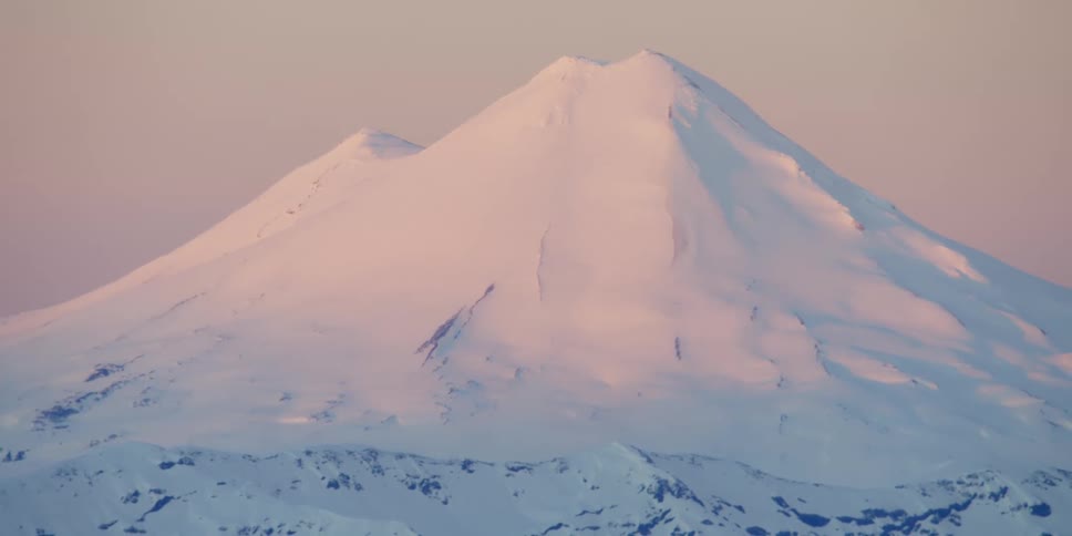 A snowy volcano at sunset