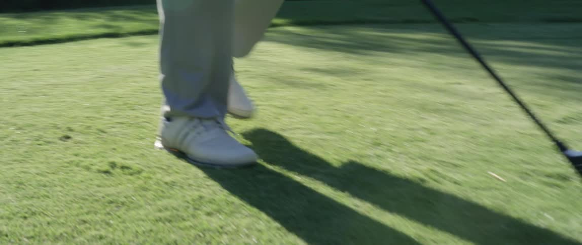 A golfer places their ball on the green