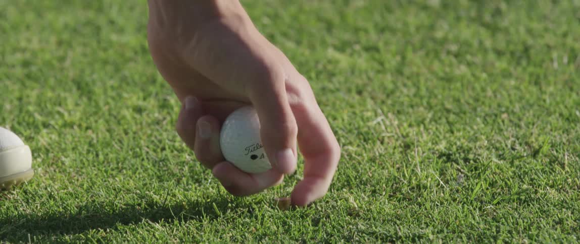 A man places a tee and golf ball