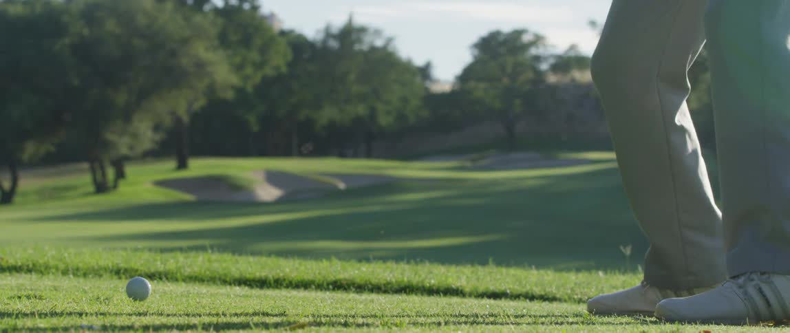 A golfer swings and hits a golf ball