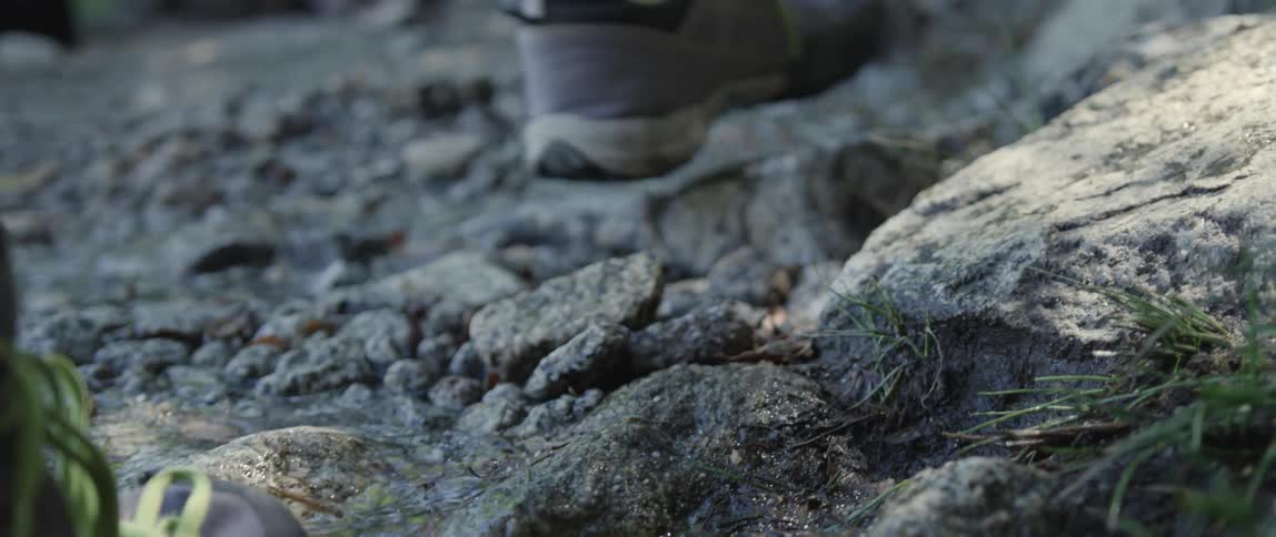 A person walks up a wet rock