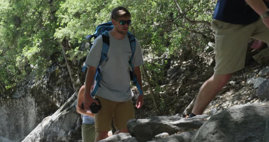 Three young men hiking on a trail around some boulders