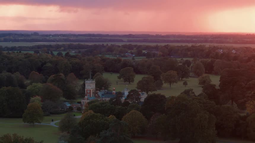 A storm dumps rain on the horizon of a large country manor estate