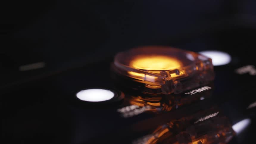 Buttons and knobs on a control panel are labeled and lighted up