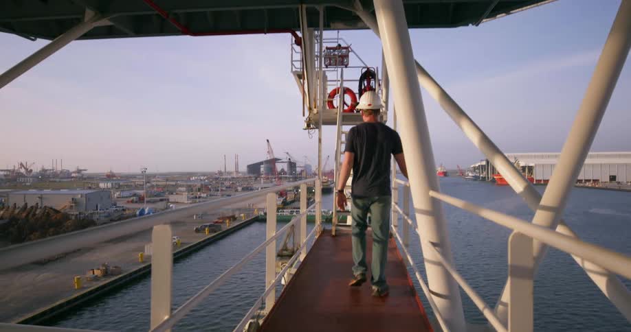 A man walks along a deck on a shipping boat