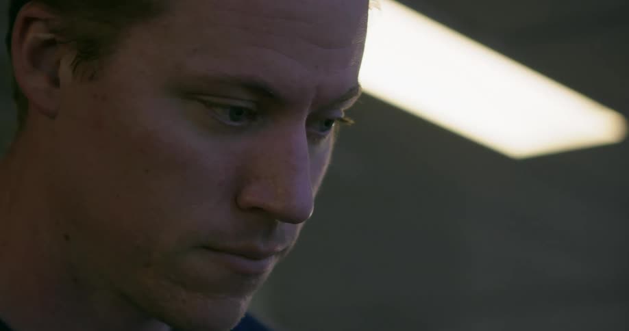 A young white man looks at something indoors