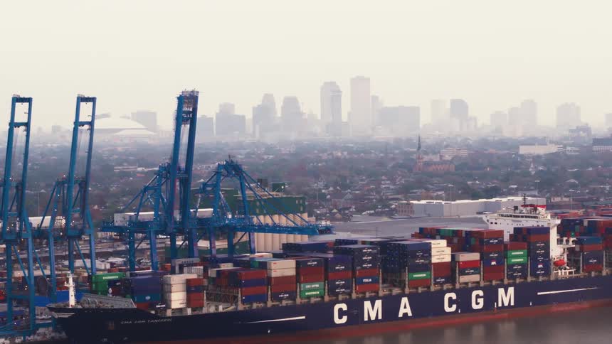 Shipping containers are piled up high and close in a shipping yard near a city