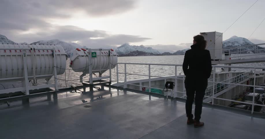 Woman stands on the deck of a traveling ship