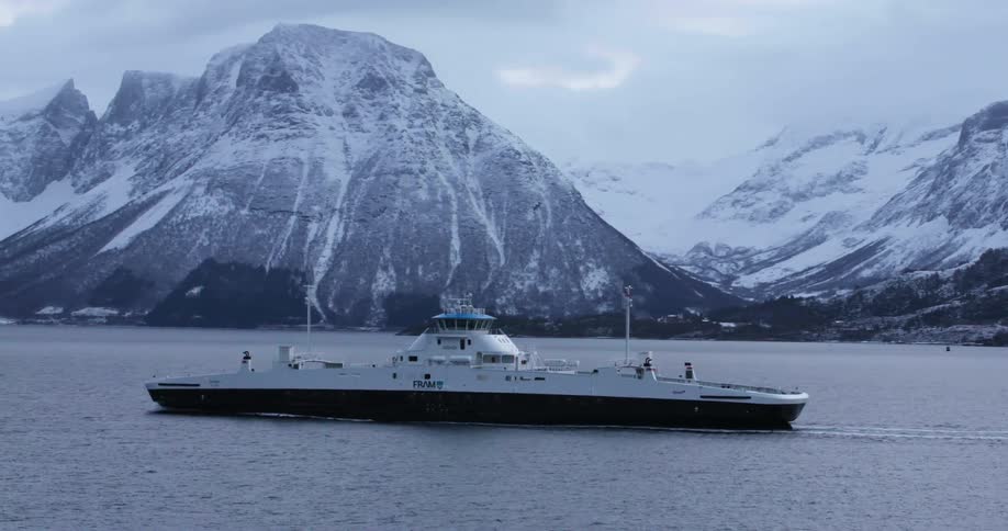 Ferry boat travels across the sea with the snow capped mountains in the background