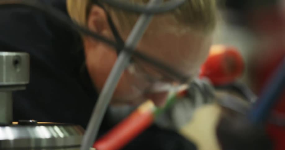 A woman holding a hammer looks at equipment