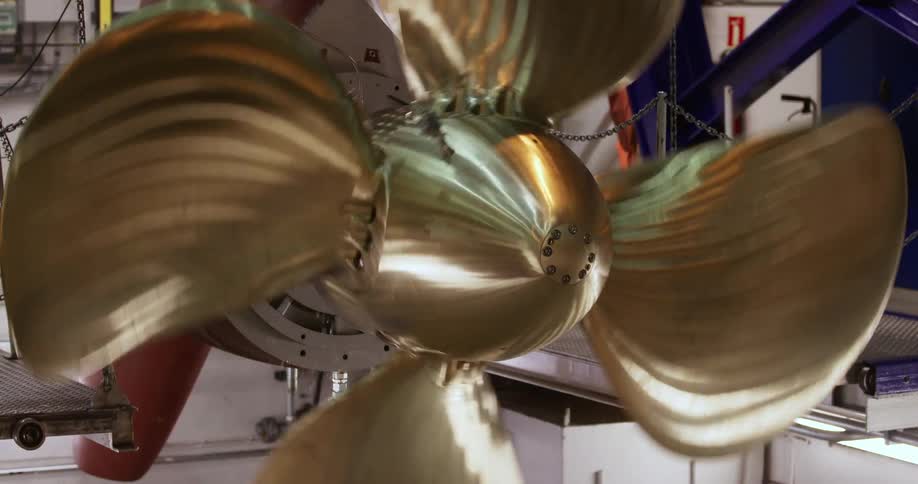 Large golden blades on a ship engine turn in a test run in a factory
