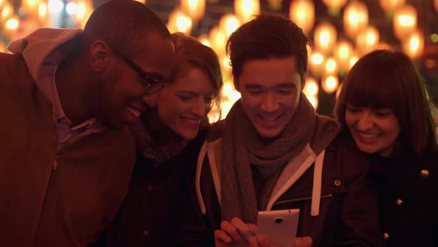 Friends gathered looking at a cell phone and laughing