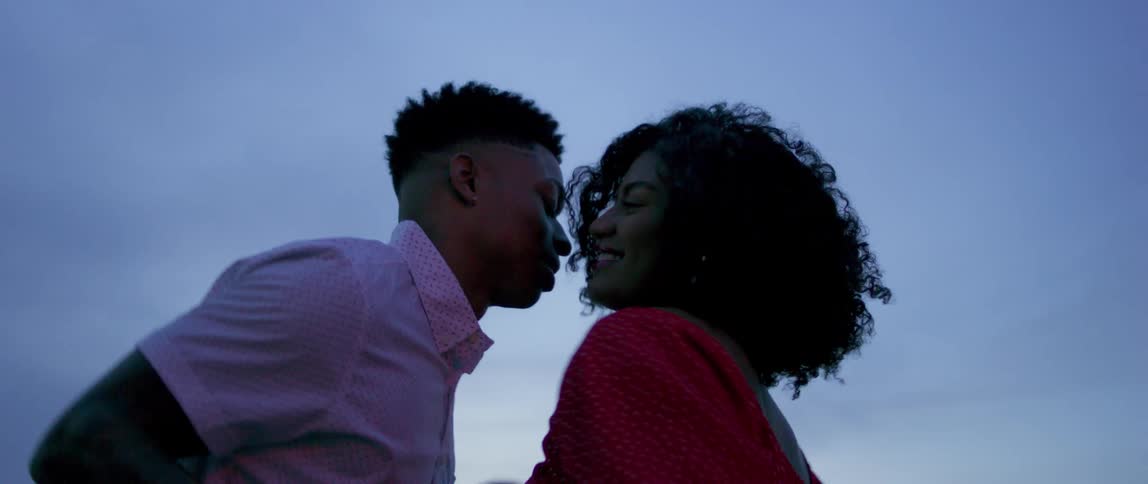 Black man and woman dance outdoors at dusk