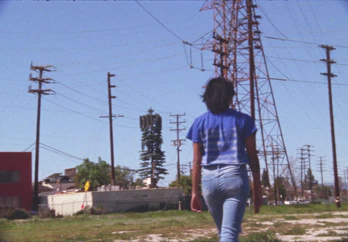 Woman walks under power lines and transmission towers in a town
