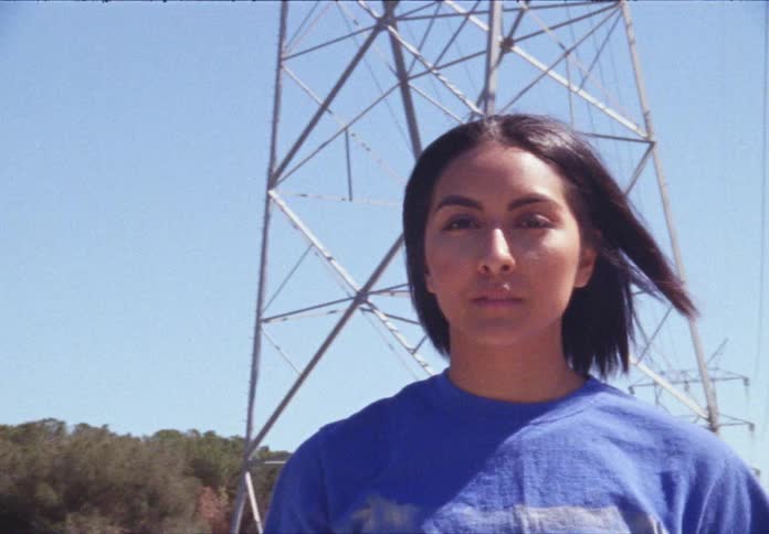 A hispanic teenager walks near transmission towers