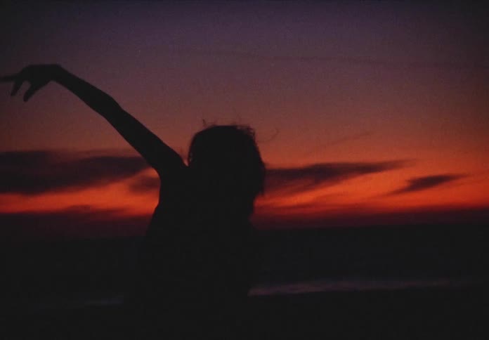 A woman dances outdoors as the sun goes down