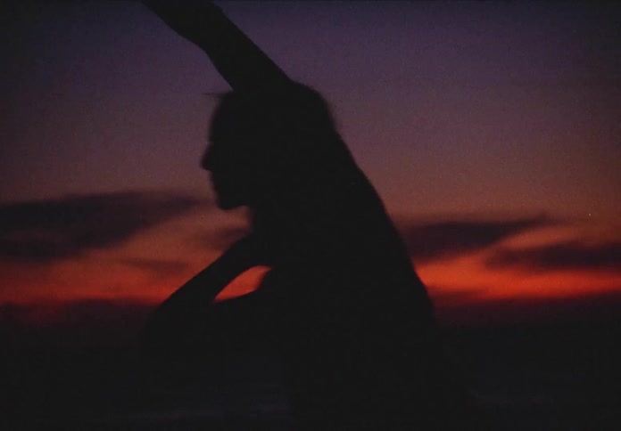 A silhouette of a female dancer dances at sunset