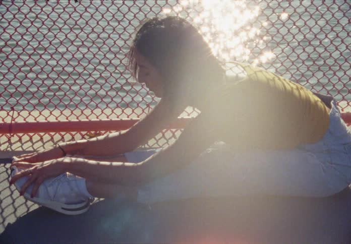 A woman does yoga on a fenced pier next to the water