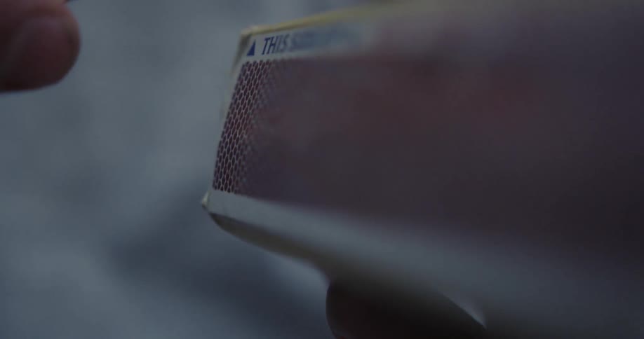 A hand striking a match on a matchbox
