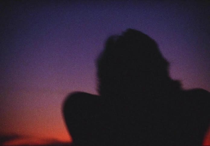 A woman dances outdoors as the sun goes down