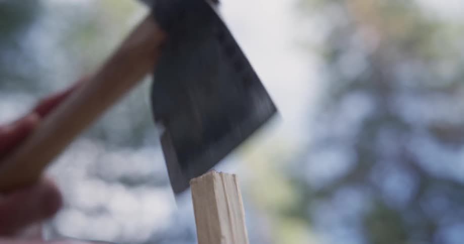 Person shaving a piece of wood with a hatchet