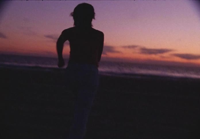 A white male runs down the beach to the water