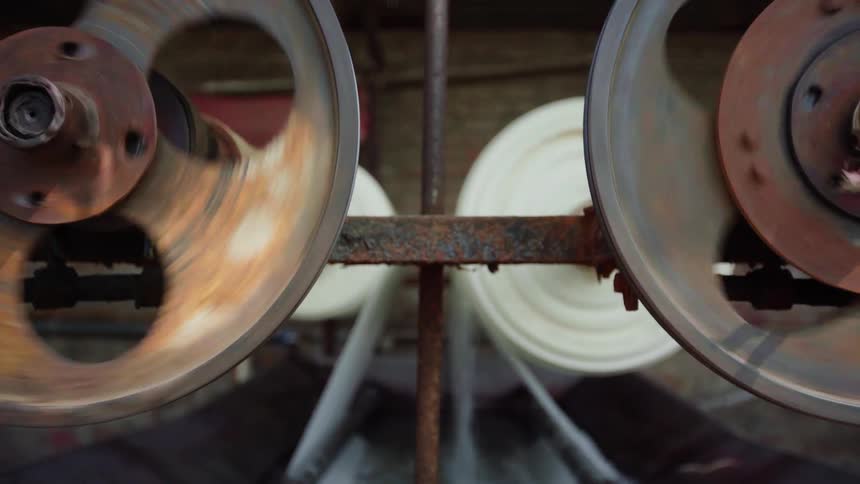 The gears of a machine spinning rolls of cloth through water