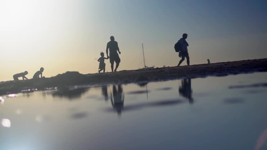 A father and child hold hands and run on a beach