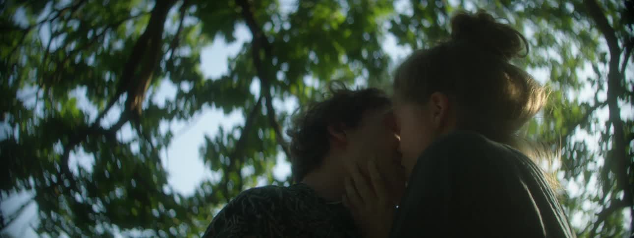 Two teenagers kiss out in the woods