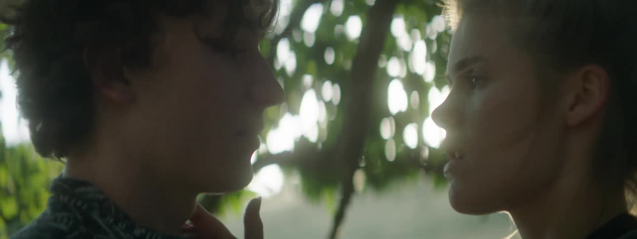 Two teens kissing beneath trees