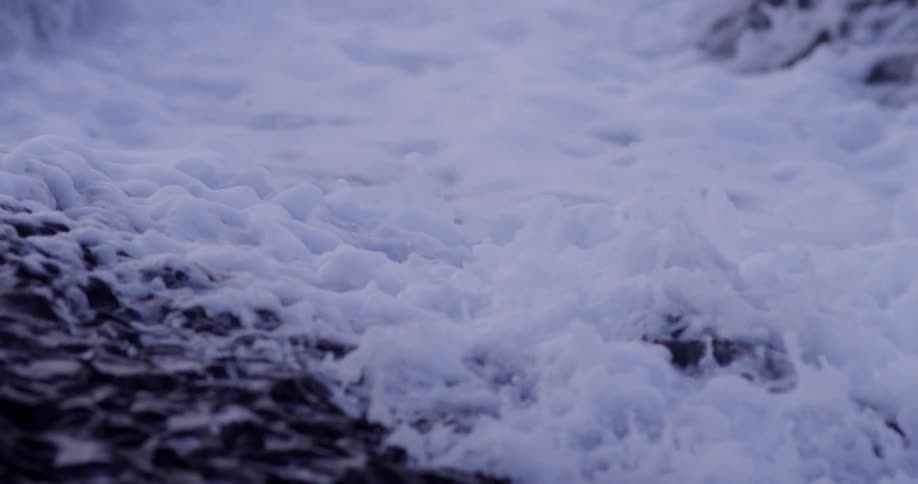 A foamy wave crashes on a rocky shore