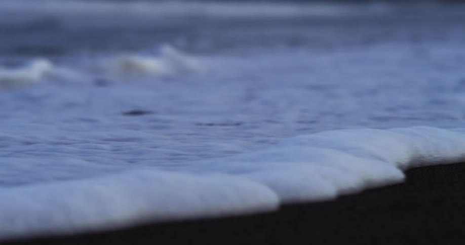 A foamy tide rolls up on a beach
